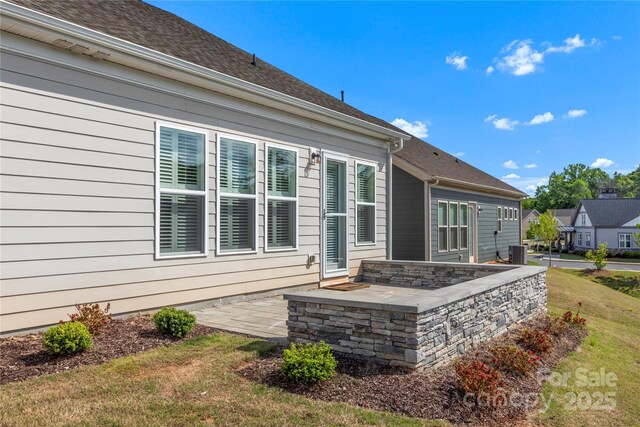 rear view of property with a lawn, a patio, and central AC
