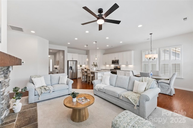 329 Brambling Ct, Wesley Chapel, NC 28110 - living area with wood finished floors, ceiling fan, a chandelier, recessed lighting, and a fireplace