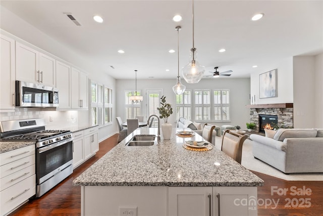 329 Brambling Ct, Wesley Chapel, NC 28110 - kitchen with appliances with stainless steel finishes, a sink, a ceiling fan, open floor plan, and a center island with sink
