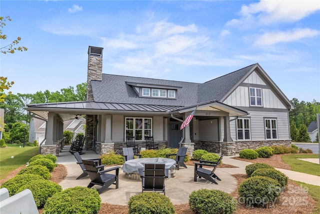 329 Brambling Ct, Wesley Chapel, NC 28110 - back of property featuring a standing seam roof, stone siding, a porch, and a shingled roof
