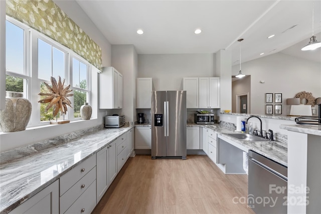 329 Brambling Ct, Wesley Chapel, NC 28110 - kitchen with stainless steel appliances, a sink, a peninsula, light stone counters, and high vaulted ceiling