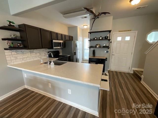 kitchen featuring open shelves, a sink, appliances with stainless steel finishes, a peninsula, and backsplash