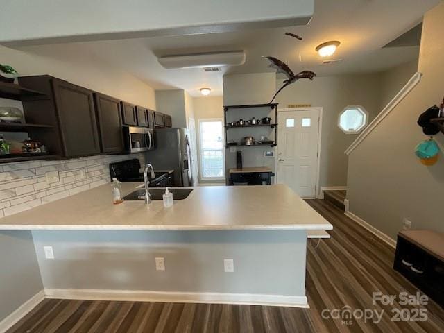 kitchen with stainless steel appliances, open shelves, a peninsula, and a sink