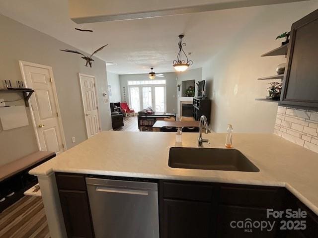 kitchen with dishwasher, a sink, open floor plan, and light countertops