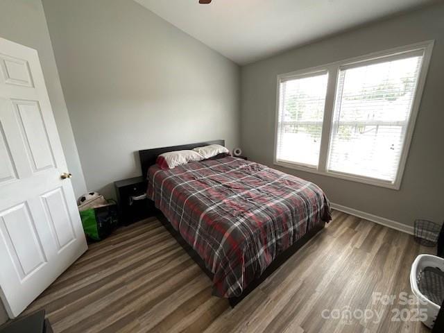 bedroom with lofted ceiling, wood finished floors, and baseboards