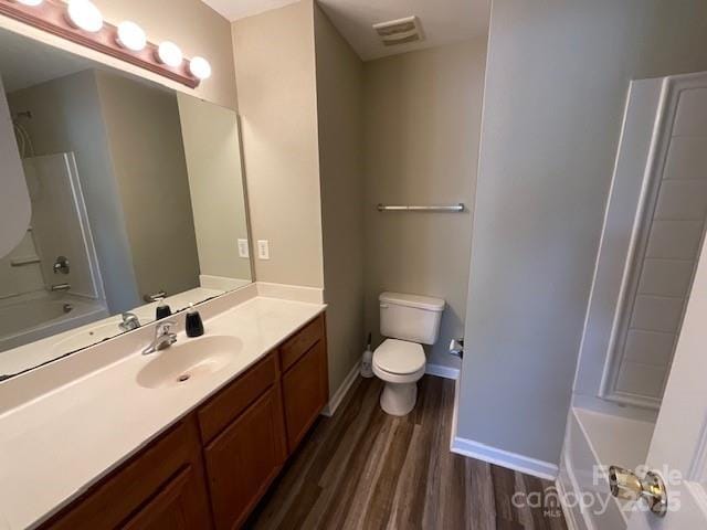 bathroom with vanity, toilet, visible vents, baseboards, and wood finished floors