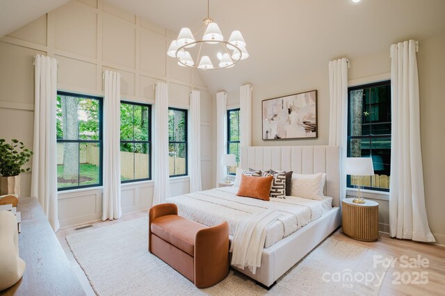 1807 Arnold Dr, Charlotte, NC 28205 - bedroom featuring a decorative wall, a chandelier, vaulted ceiling, and light wood finished floors