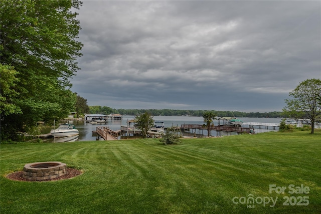 view of dock featuring a yard, an outdoor fire pit, and a water view