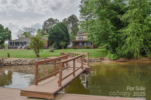dock area featuring a deck with water view and a yard