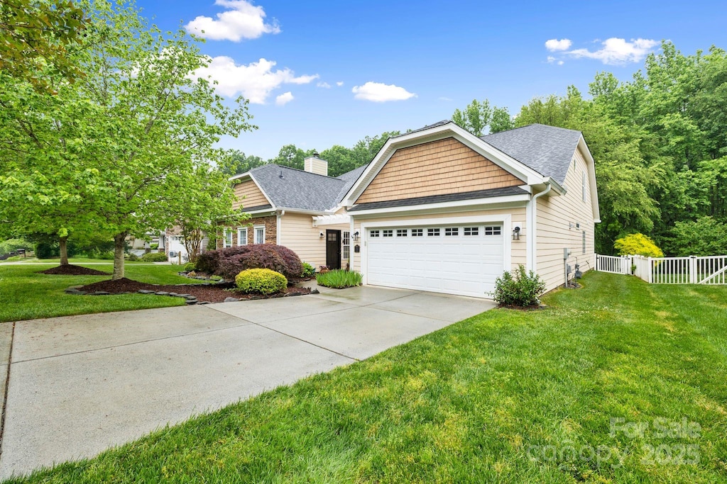 view of front of property with driveway, a chimney, fence, a front lawn, and a garage