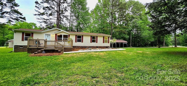 back of property featuring a detached carport, a deck, crawl space, and a yard