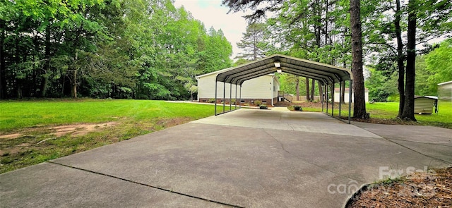 view of property's community featuring a yard, a detached carport, and concrete driveway