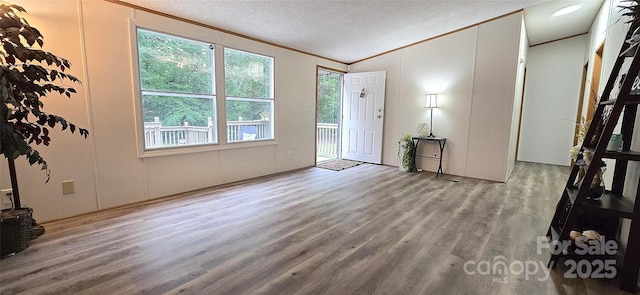 foyer featuring wood finished floors, a healthy amount of sunlight, lofted ceiling, and crown molding
