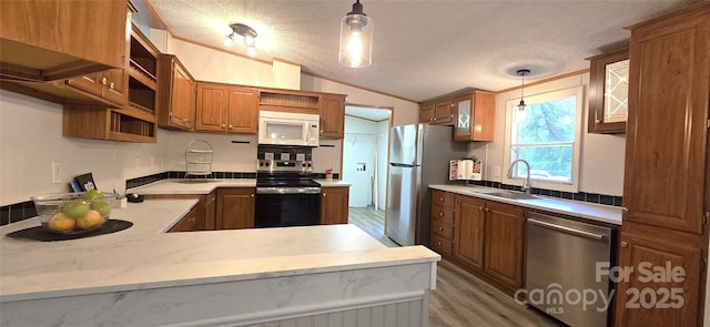 kitchen with a sink, open shelves, vaulted ceiling, a textured ceiling, and appliances with stainless steel finishes