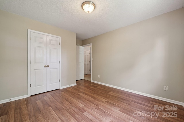 3038 Twin Peaks Ct, Monroe, NC 28110 - unfurnished bedroom featuring wood finished floors, baseboards, a closet, and a textured ceiling