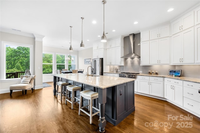 kitchen featuring a sink, appliances with stainless steel finishes, tasteful backsplash, and wall chimney exhaust hood