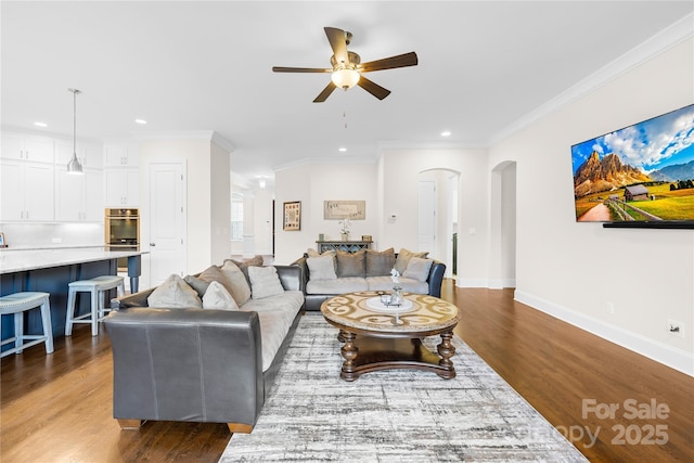 living area featuring arched walkways, a ceiling fan, baseboards, and recessed lighting