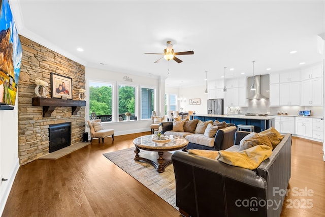 living area with light wood-type flooring, a fireplace, a ceiling fan, and recessed lighting