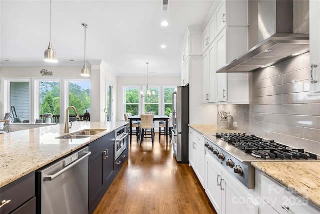 kitchen with a sink, white cabinetry, wall chimney range hood, tasteful backsplash, and appliances with stainless steel finishes