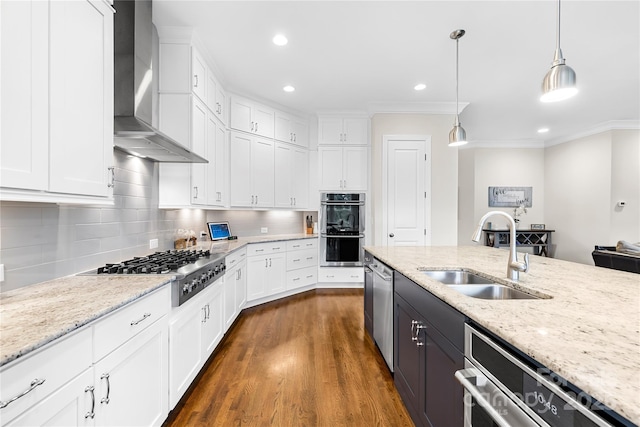 kitchen featuring a sink, wall chimney range hood, white cabinetry, and appliances with stainless steel finishes