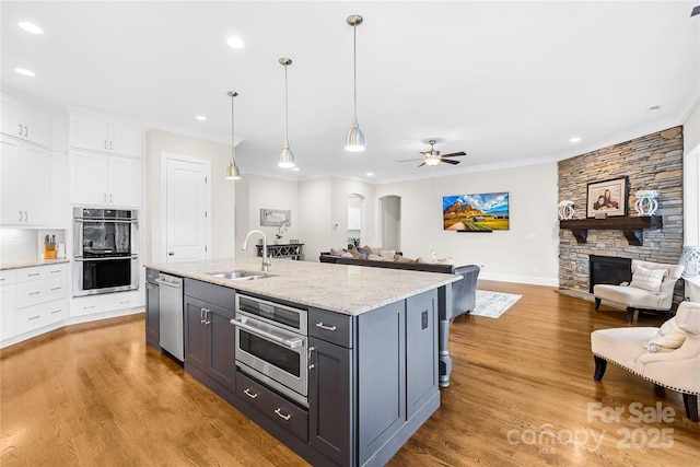 kitchen featuring recessed lighting, a sink, open floor plan, stainless steel appliances, and white cabinets
