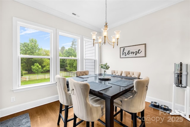 dining space with baseboards, an inviting chandelier, visible vents, and wood finished floors