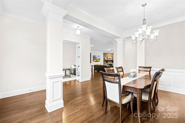 dining space with crown molding, wood finished floors, and decorative columns