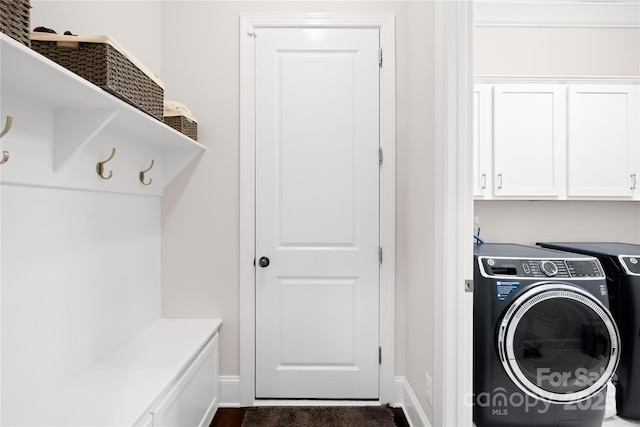 washroom with washing machine and dryer, cabinet space, and baseboards