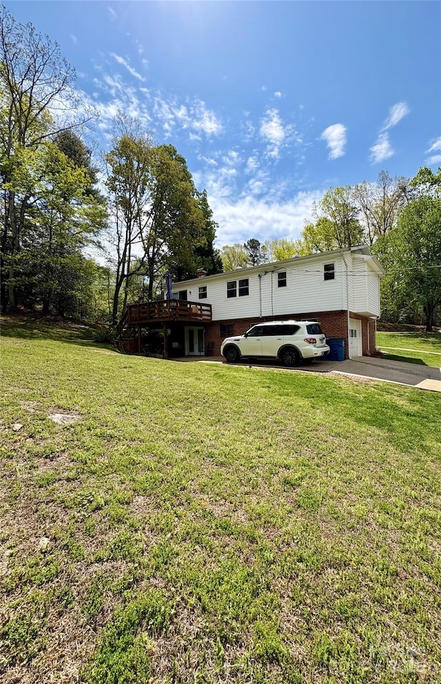 view of yard featuring concrete driveway, a wooden deck, and a garage