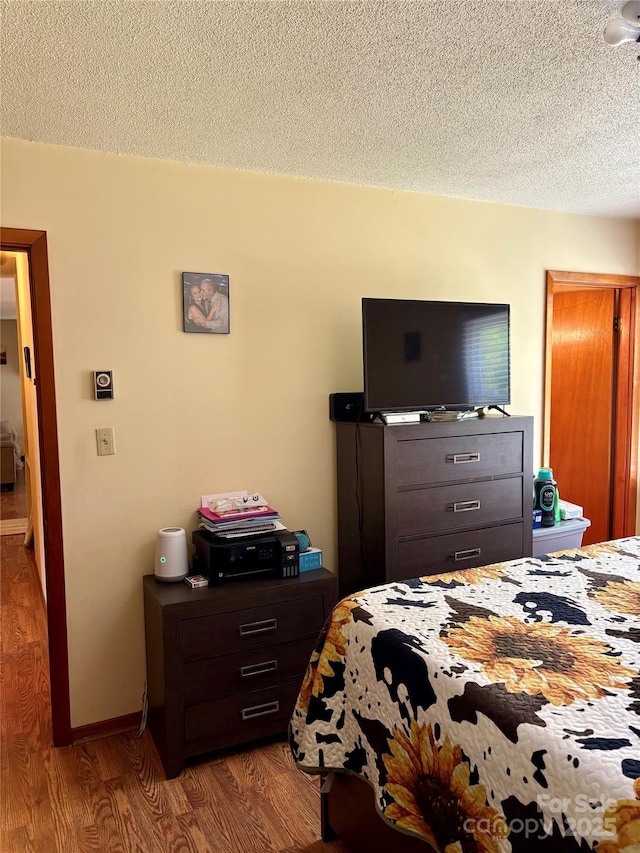 bedroom with a textured ceiling and wood finished floors
