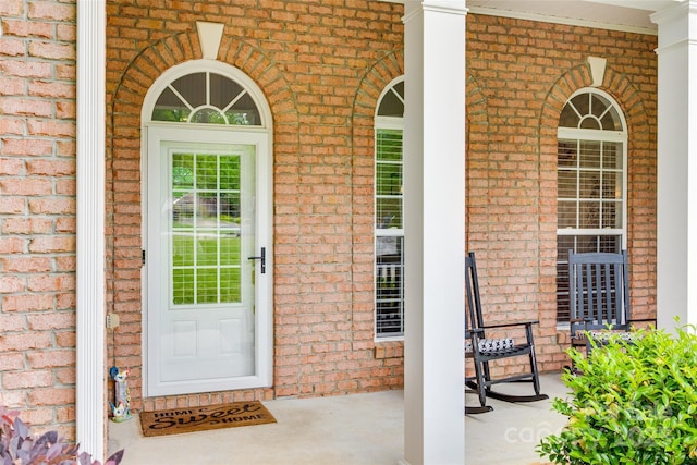 entrance to property with brick siding and covered porch