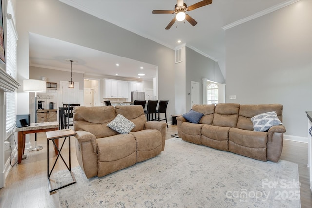 living room featuring baseboards, ornamental molding, light wood finished floors, and ceiling fan