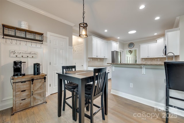 dining room featuring crown molding, recessed lighting, and light wood finished floors