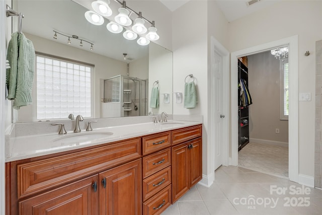 bathroom featuring double vanity, a healthy amount of sunlight, a sink, and a stall shower