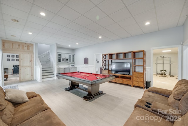 playroom with a paneled ceiling, pool table, a wainscoted wall, light wood finished floors, and a decorative wall