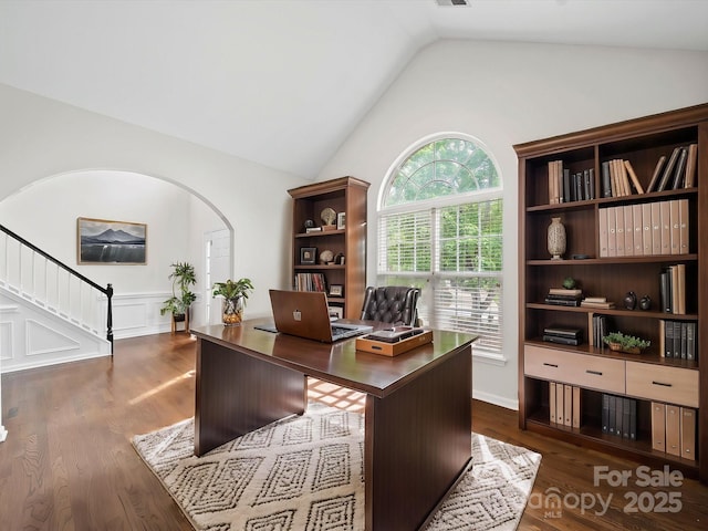 office with wainscoting, arched walkways, dark wood-type flooring, and vaulted ceiling