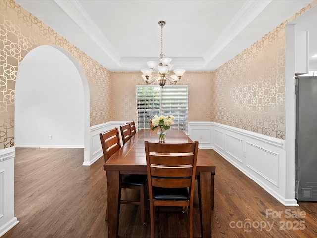 dining room with arched walkways, a chandelier, wallpapered walls, wainscoting, and dark wood-style floors