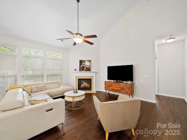 living room featuring a fireplace with flush hearth, dark wood-style flooring, ceiling fan, and vaulted ceiling