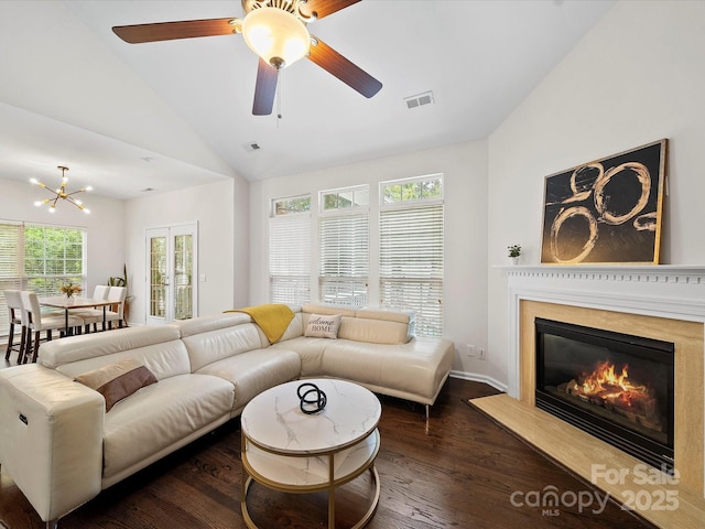living area featuring a high end fireplace, visible vents, vaulted ceiling, and wood finished floors