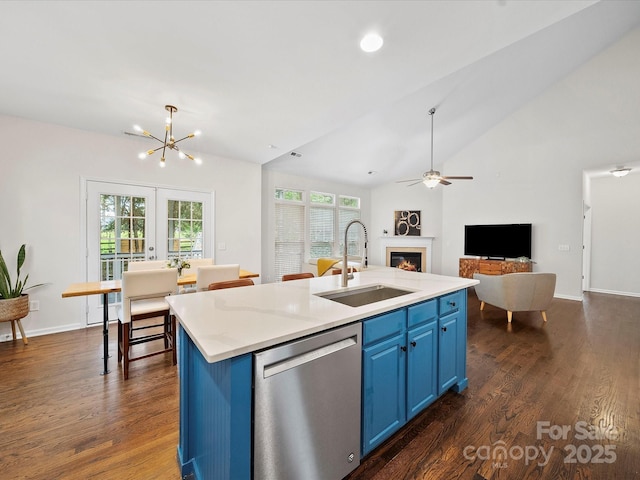 kitchen featuring blue cabinets, stainless steel dishwasher, a glass covered fireplace, a sink, and open floor plan