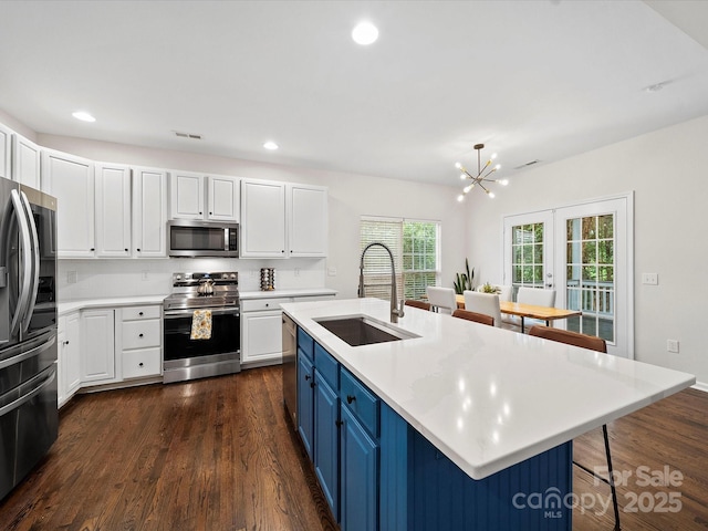 kitchen featuring dark wood finished floors, stainless steel appliances, light countertops, white cabinets, and a sink