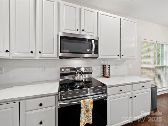 kitchen with tasteful backsplash, white cabinetry, stainless steel appliances, and light countertops