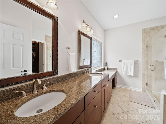 bathroom featuring a stall shower, double vanity, a sink, and tile patterned floors