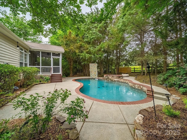 outdoor pool featuring a fenced backyard, a patio, and a sunroom