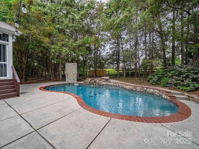 outdoor pool with a patio and a fenced backyard