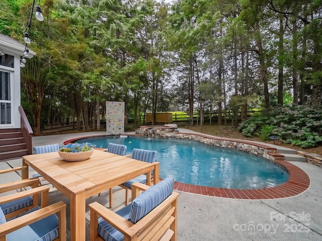 outdoor pool with an in ground hot tub, outdoor dining space, and a fenced backyard
