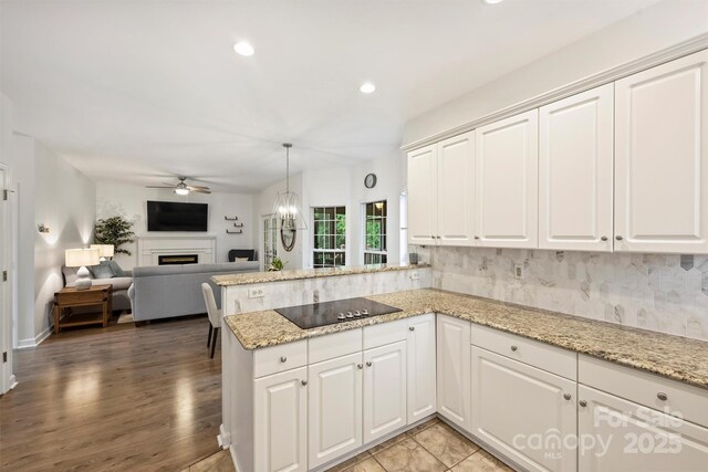 6723 Joliette Ln, Charlotte, NC 28277 - kitchen featuring black electric stovetop, a ceiling fan, a peninsula, recessed lighting, and a fireplace