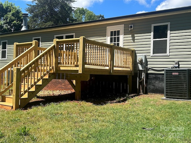 wooden terrace with central air condition unit, a lawn, and stairway