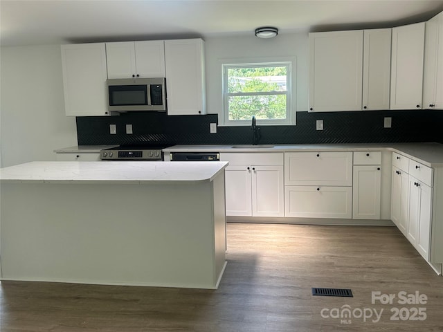 kitchen with a sink, backsplash, stainless steel appliances, and visible vents