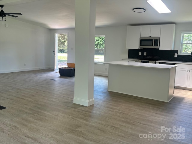 kitchen with stainless steel microwave, light wood-style flooring, and open floor plan